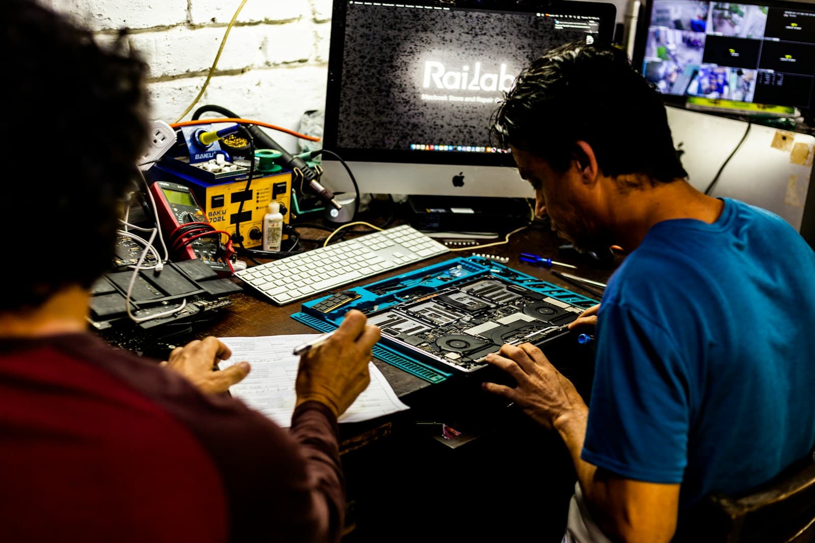 Technicians performing chip-level repair on a computer motherboard